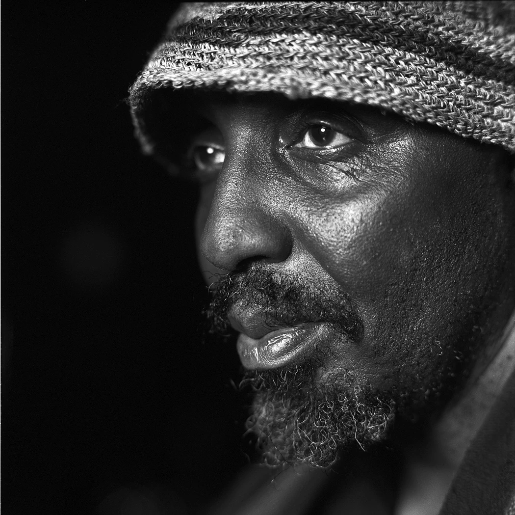 A black-and-white portrait of William Parker wearing a woven hat