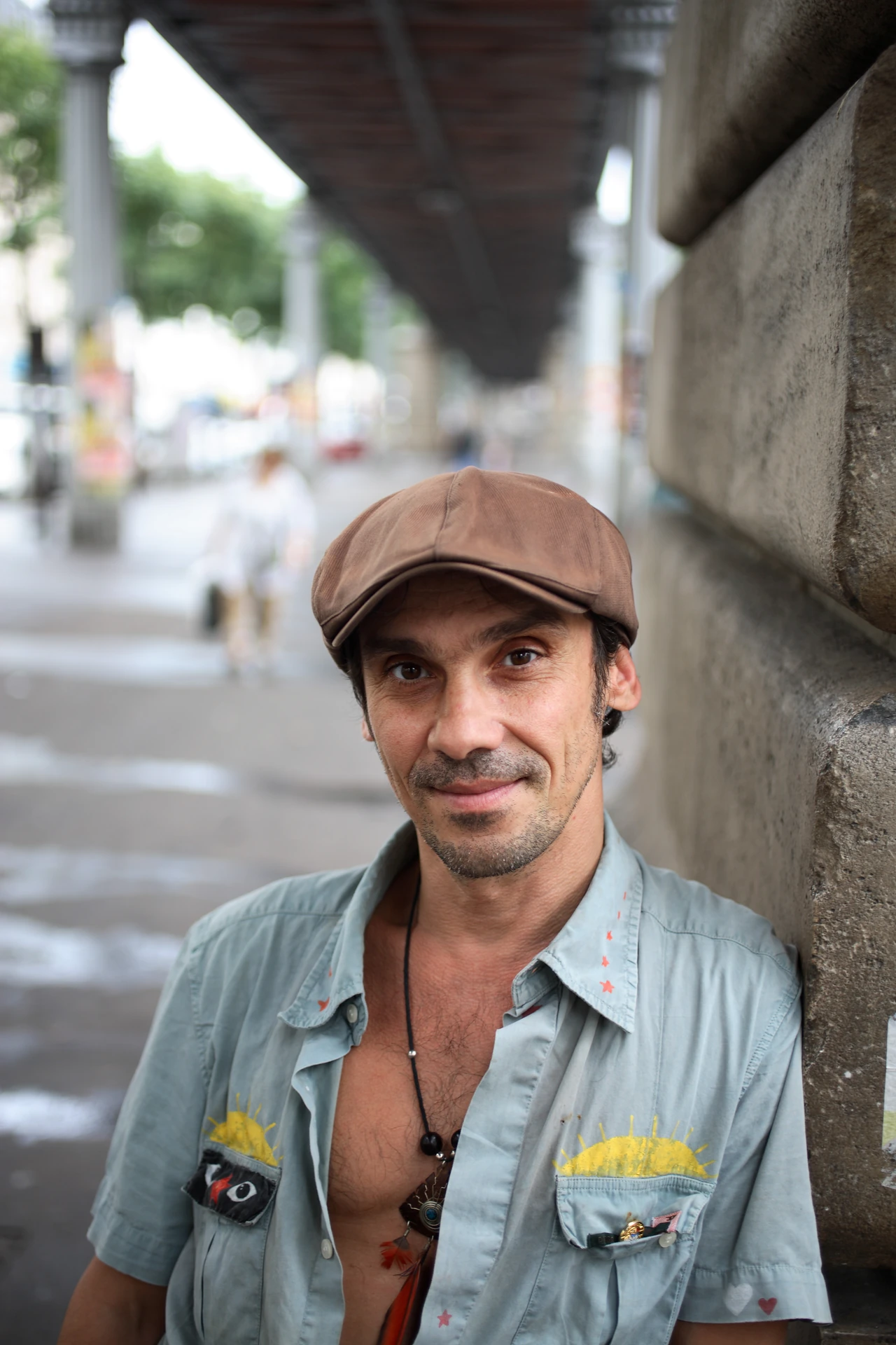 Manu Chao wearing a flat cap in a street portrait