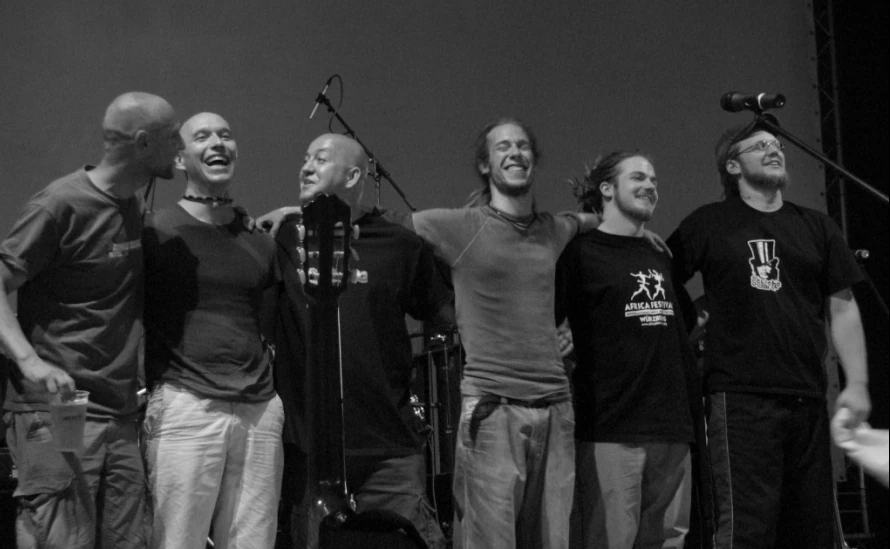 Jahcoustix with the musicians of Dubios Neighbourhood in a black-and-white stage photograph