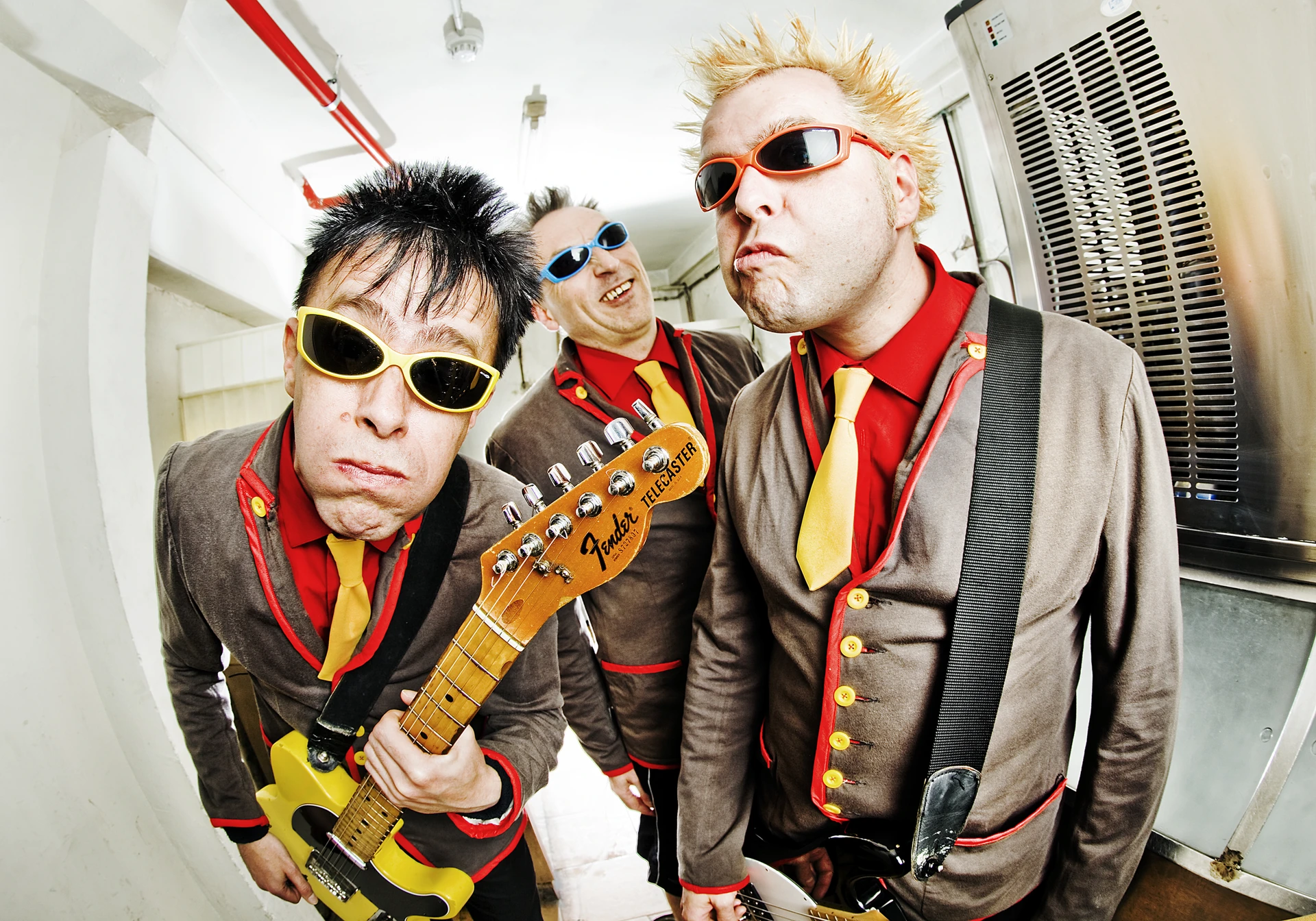 Trzech muzyków The Toy Dolls z gitarą i w kolorowych okularach