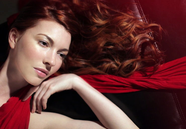 Chrysta Bell with flowing red hair against a red background