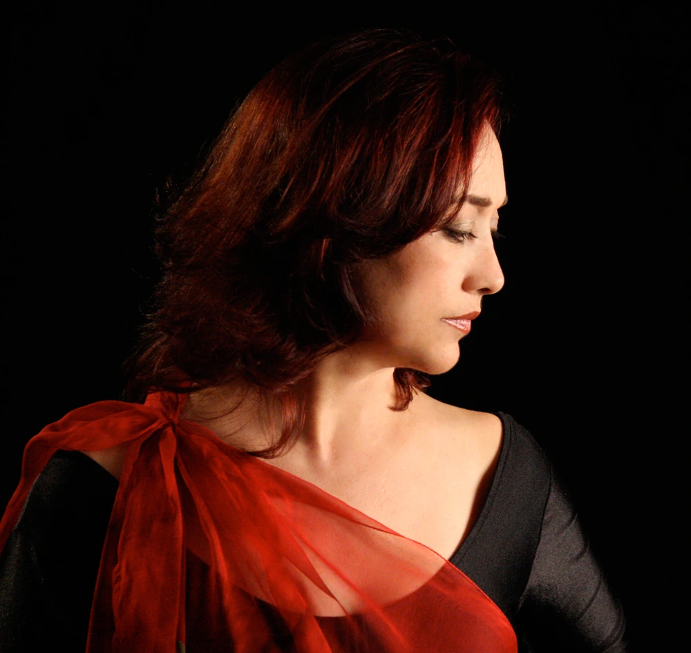 Mamak Khadem wearing a red scarf against a dark background