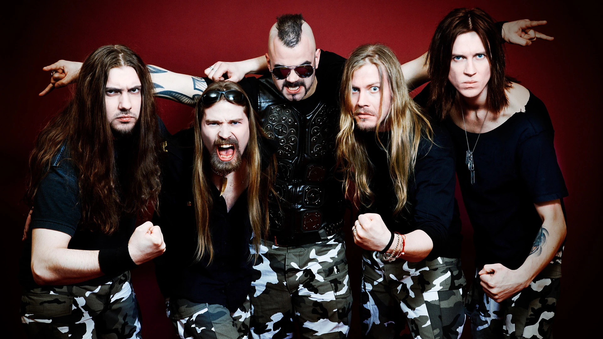 Sabaton musicians in a group photograph against a dark-red background