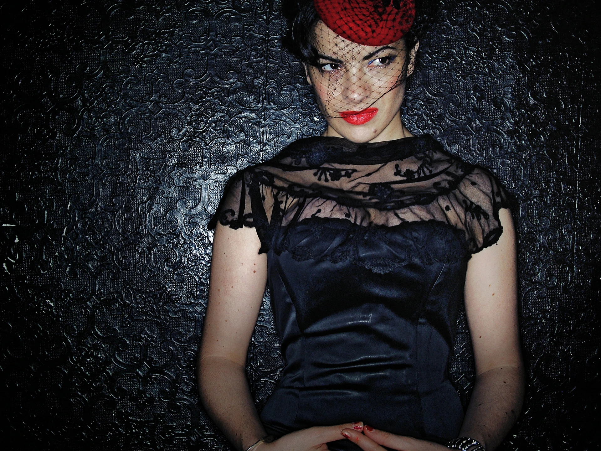 Camille O’Sullivan w czarnej sukni i czerwonym nakryciu głowy
