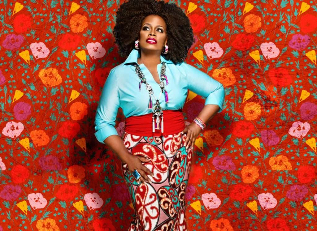Dianne Reeves wearing a turquoise blouse against a colourful floral background