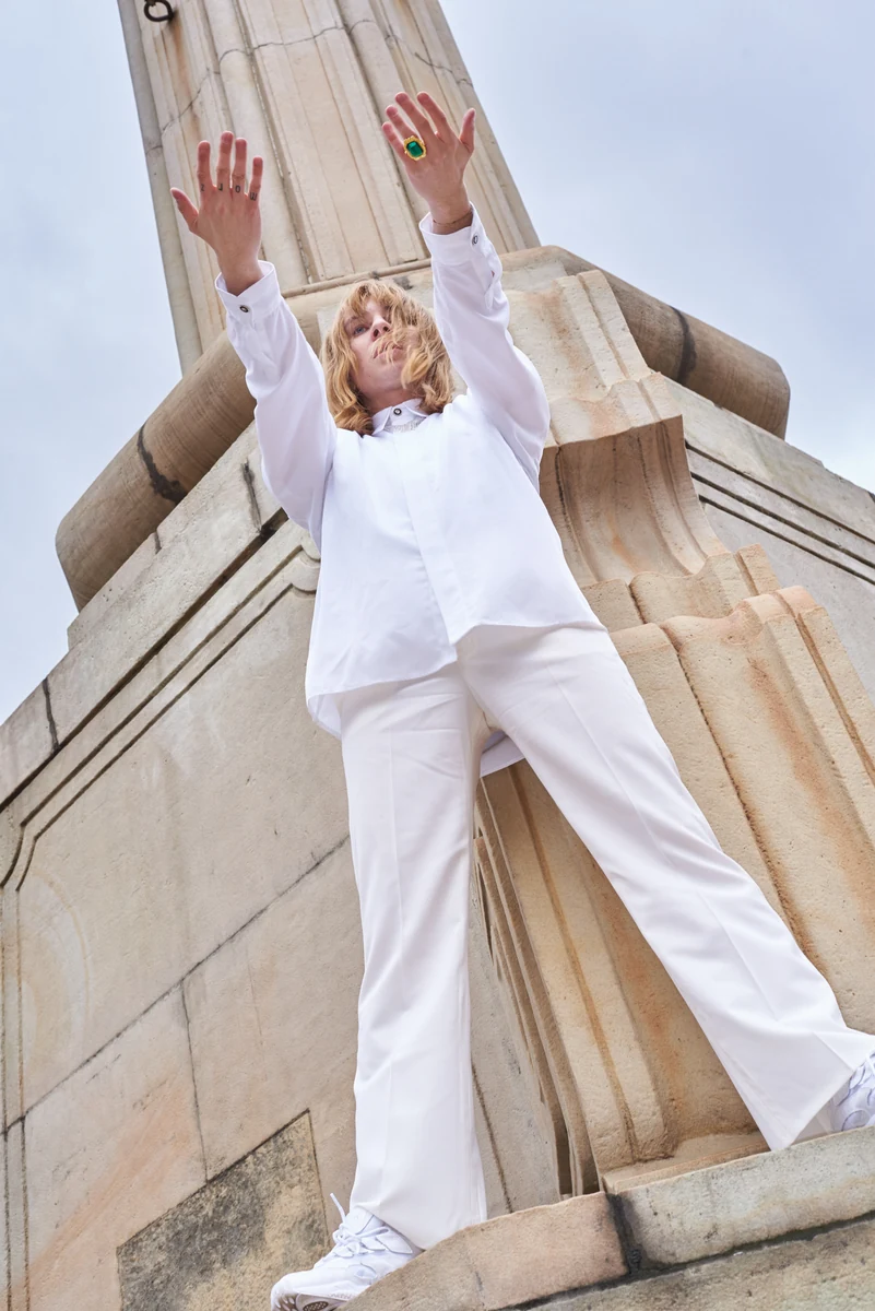 Ralph Kamiński in a light outfit beside columns