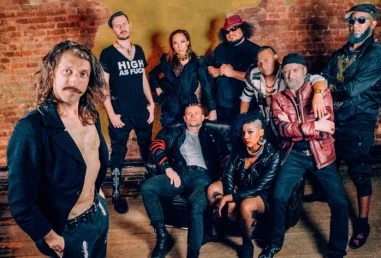 Muzycy Gogol Bordello na wspólnej fotografii przy ceglanej ścianie